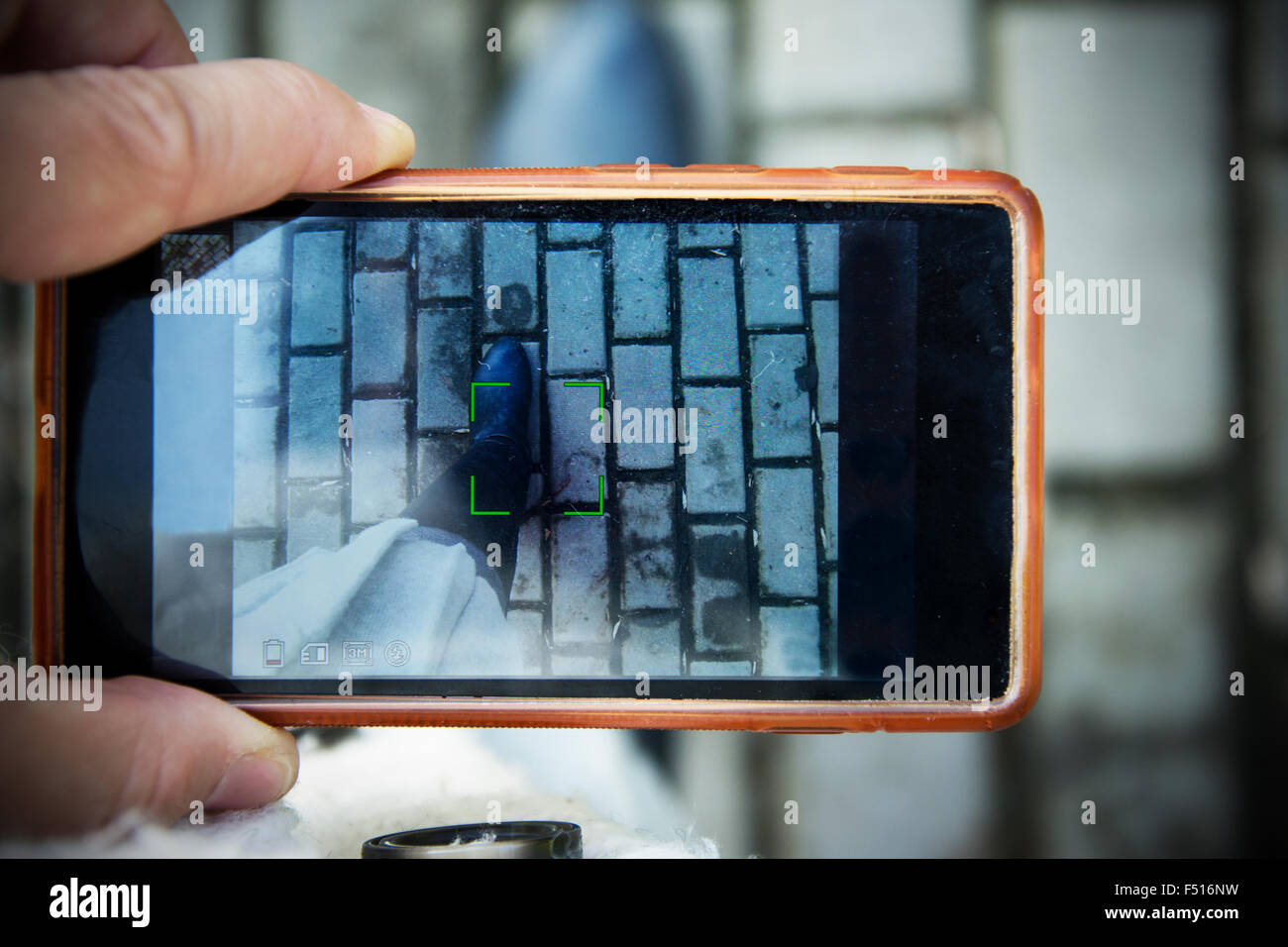 Personne prenant une photo avec l'appareil photo mobile, sur la photo bottes sur un chemin de pierre. Banque D'Images