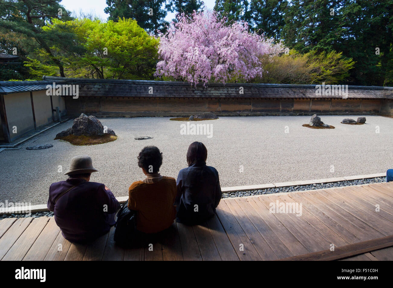 Trois visiteurs regardant célèbre jardin sec au Temple Ryoanji à Kyoto au Japon Banque D'Images