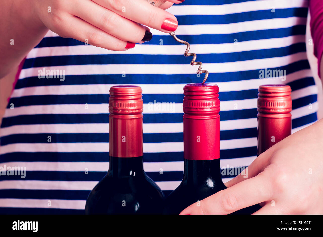 Femme tente d'ouvrir une bouteille de vin avec un tire-bouchon Banque D'Images