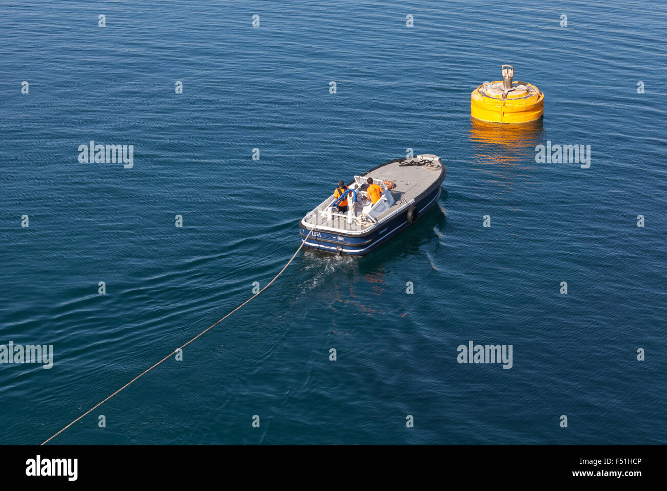 Ajaccio, France - 30 juin 2015 : Opérations portuaires, de l'homme au travail. Bateau à moteur est utilisé pour la connexion de corde sur big yellow mooring Banque D'Images