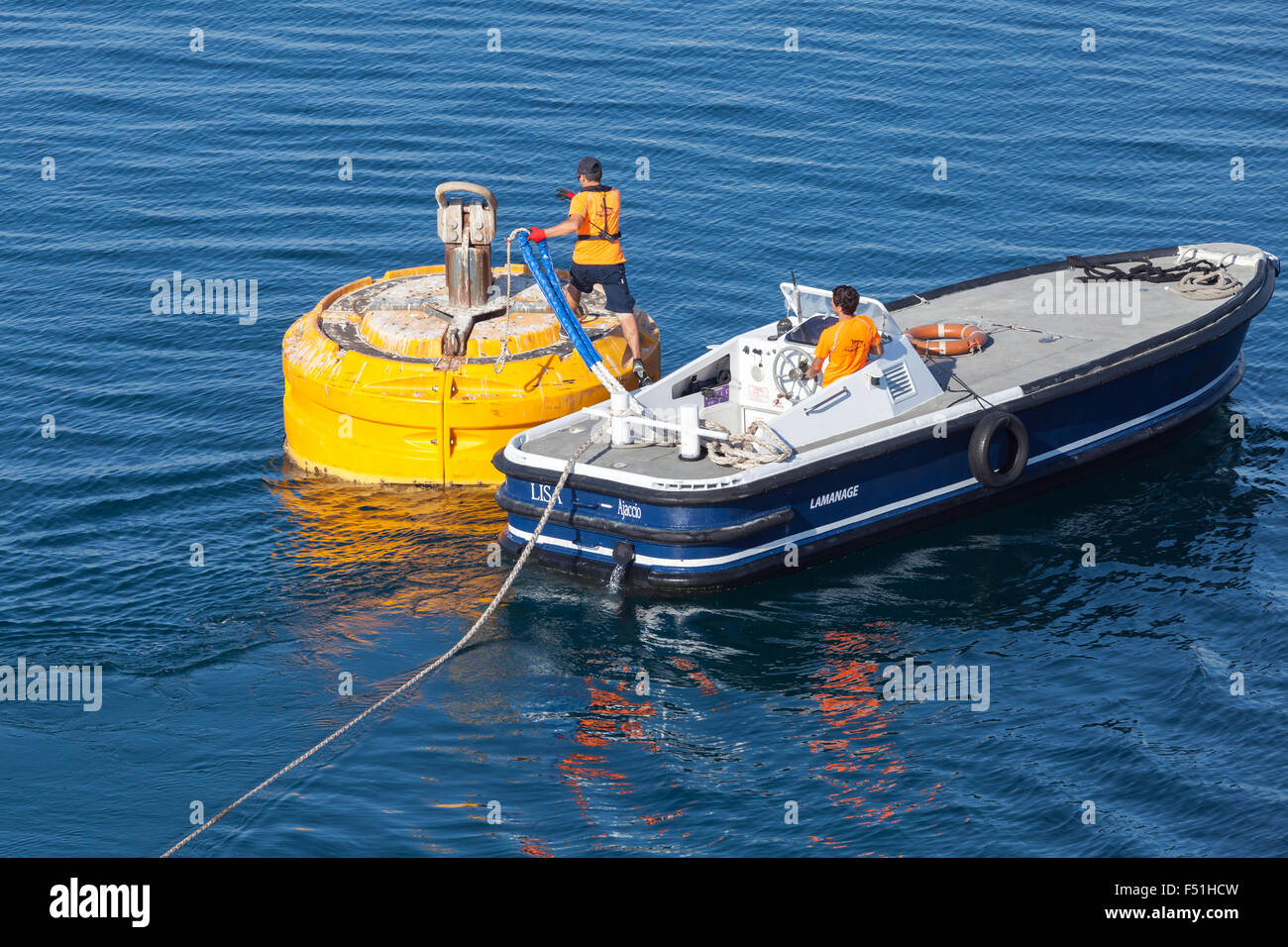 Ajaccio, France - 30 juin 2015 : Opérations portuaires, de l'homme au travail. Bateau à moteur est utilisé pour la fixation de la corde sur la bouée d'amarrage jaune Banque D'Images