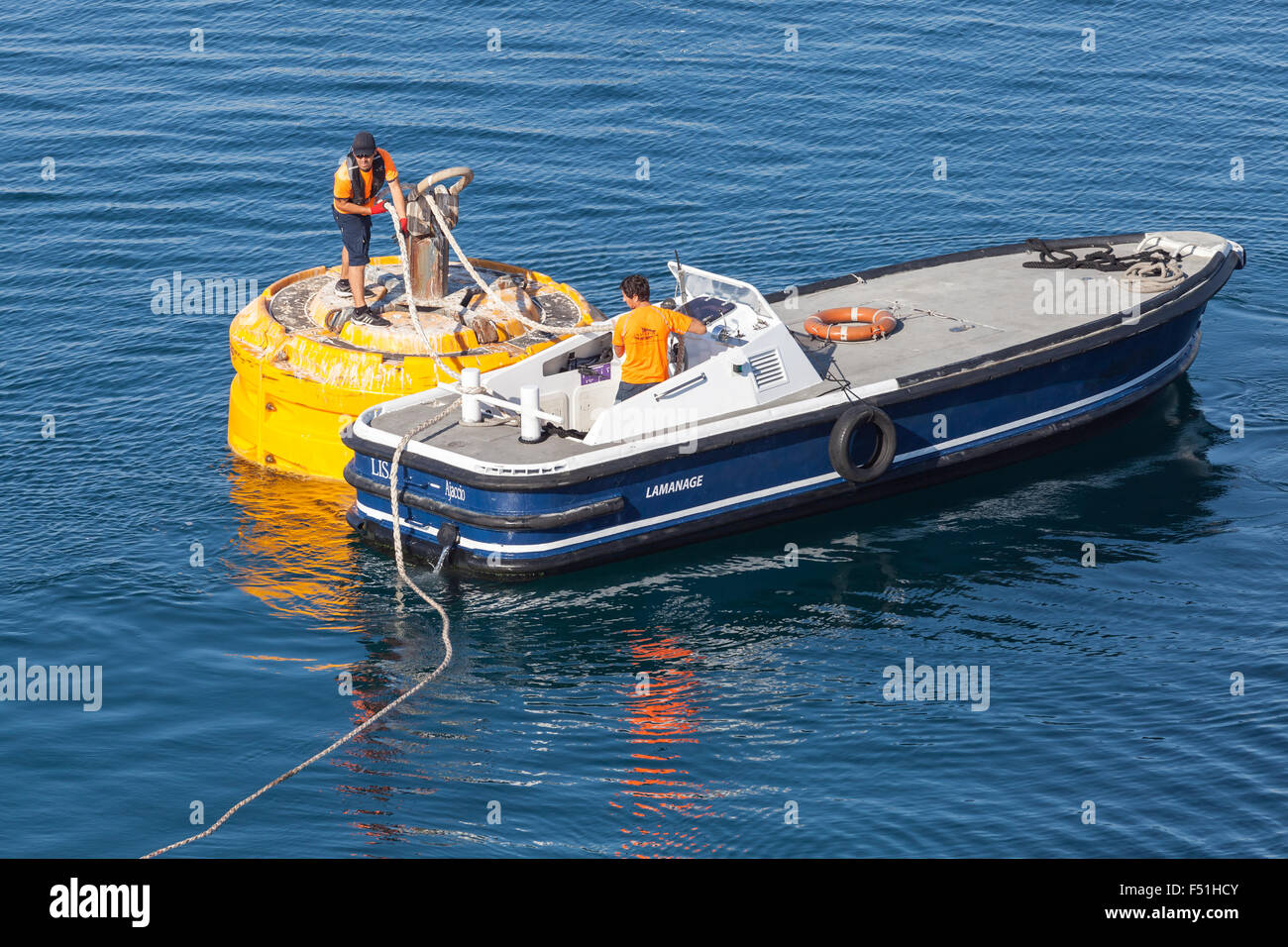 Ajaccio, France - 30 juin 2015 : Opérations portuaires, de l'homme au travail. Bateau à moteur est utilisé pour la fixation de la corde sur big yellow mooring Banque D'Images