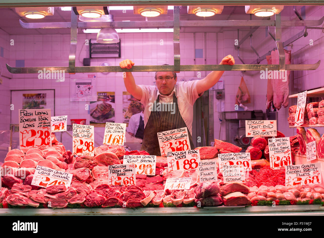 Un boucher à son échoppe à Leeds Kirkgate Market dans le West Yorkshire, au Royaume-Uni. C'est le plus grand marché couvert en Europe. Banque D'Images