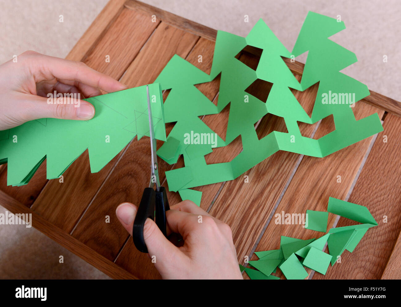 Carte verte coupe avec des ciseaux pour faire une chaîne d'arbres de Noël Banque D'Images