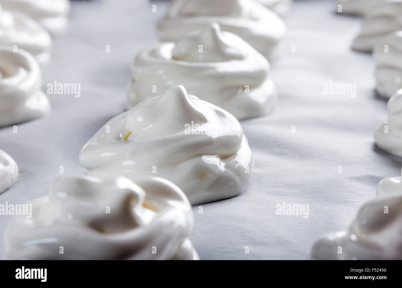 Meringues blanc sur du papier sulfurisé sur une plaque à pâtisserie Banque D'Images