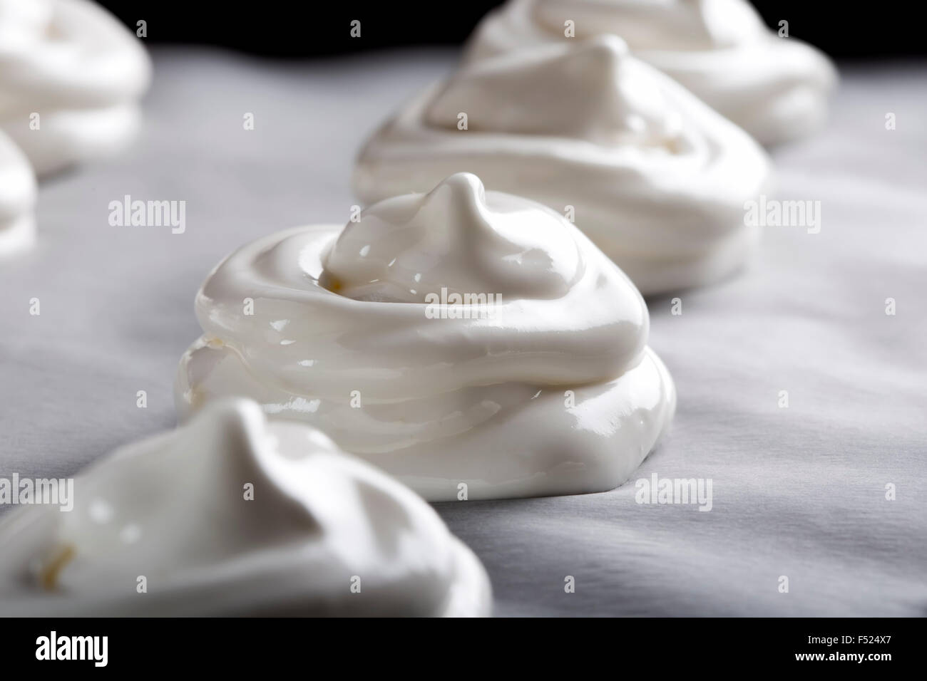 Meringues blanc sur du papier sulfurisé sur une plaque à pâtisserie Banque D'Images