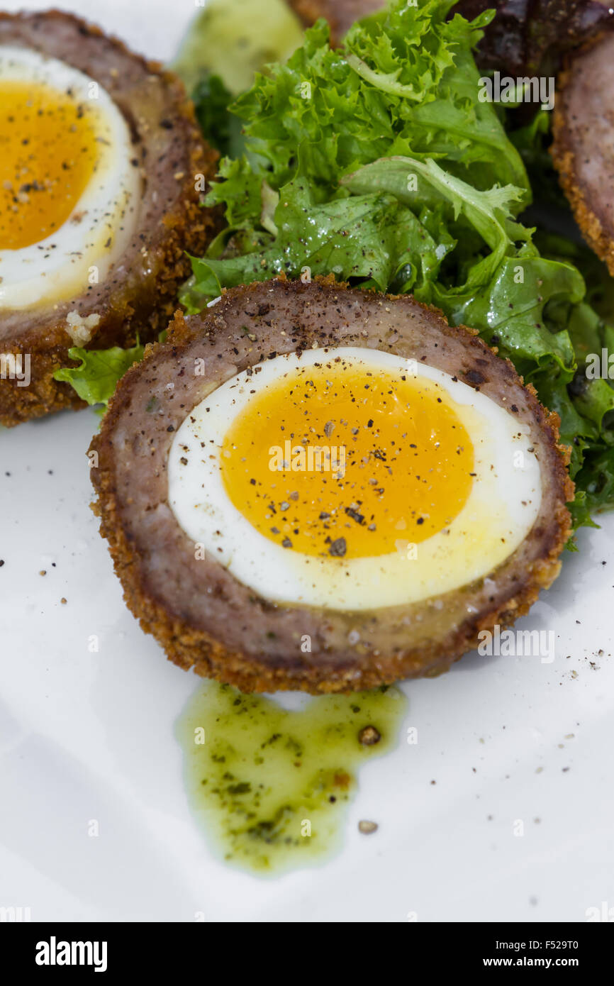 Oeufs scotch servi sur une petite assiette avec une salade verte au milieu Banque D'Images