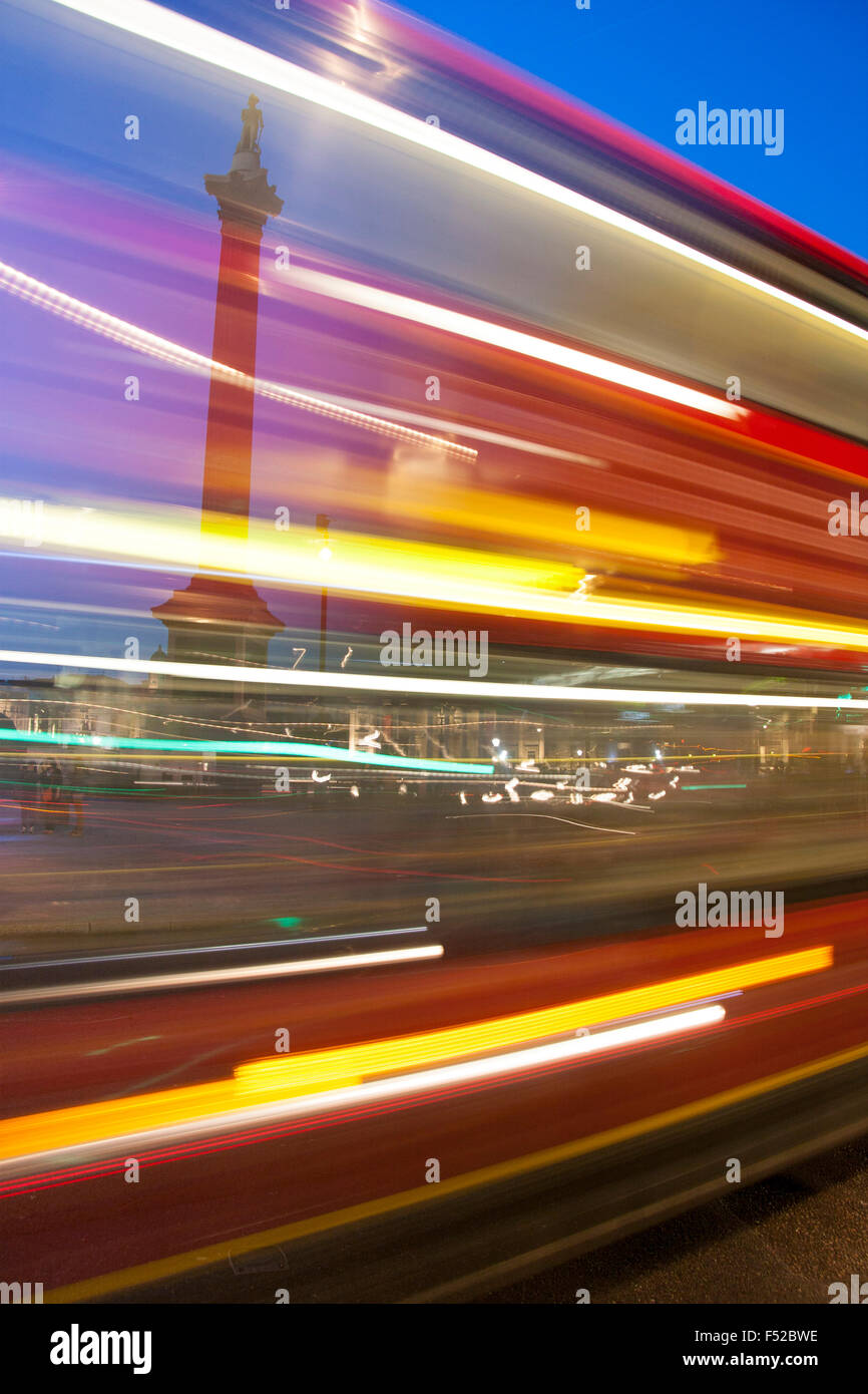 La Colonne Nelson de Trafalgar Square de nuit vue à travers des lumières mobiles de transmission bus red London London England UK Banque D'Images