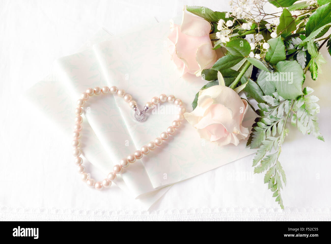 Roses rose posé sur la table avec une lettre vide et un collier de perles rose véritable du Japon. Banque D'Images