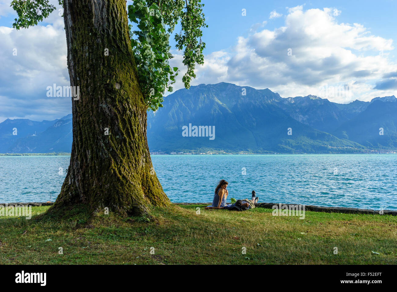 Un couple se détend sur le lac Léman en été par un bel arbre. Le lac de Genève, Suisse. Banque D'Images