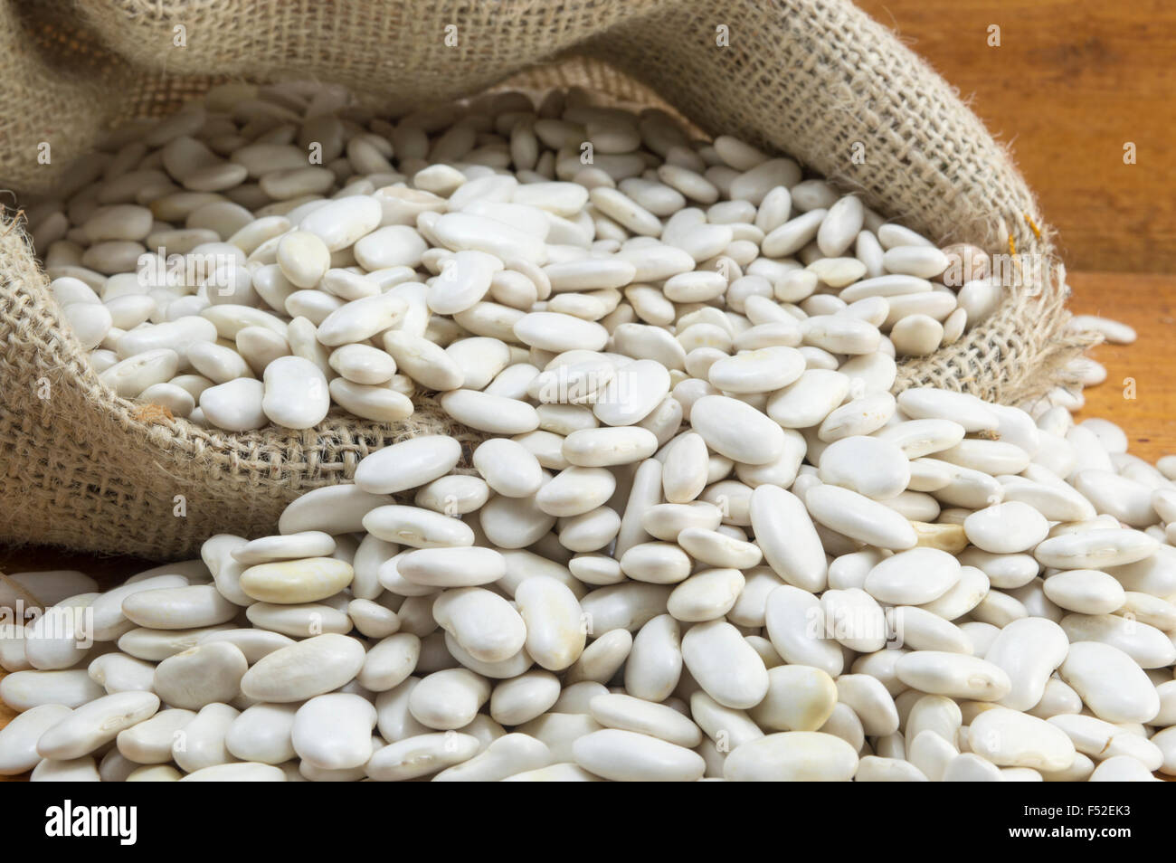 Les haricots blancs dans un sac sur une table en bois Banque D'Images