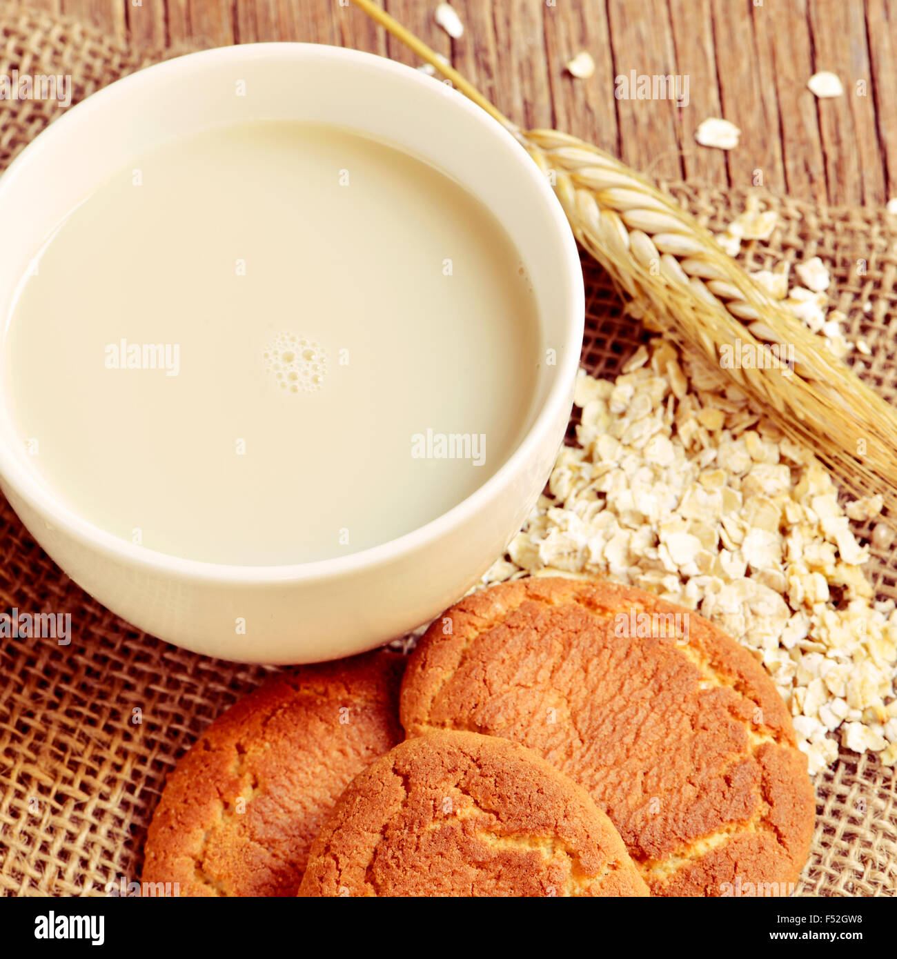 Libre d'une tasse avec du lait d'avoine, un épi de blé, quelques flocons d'avoine et quelques biscuits digestive sur une table en bois rustique Banque D'Images