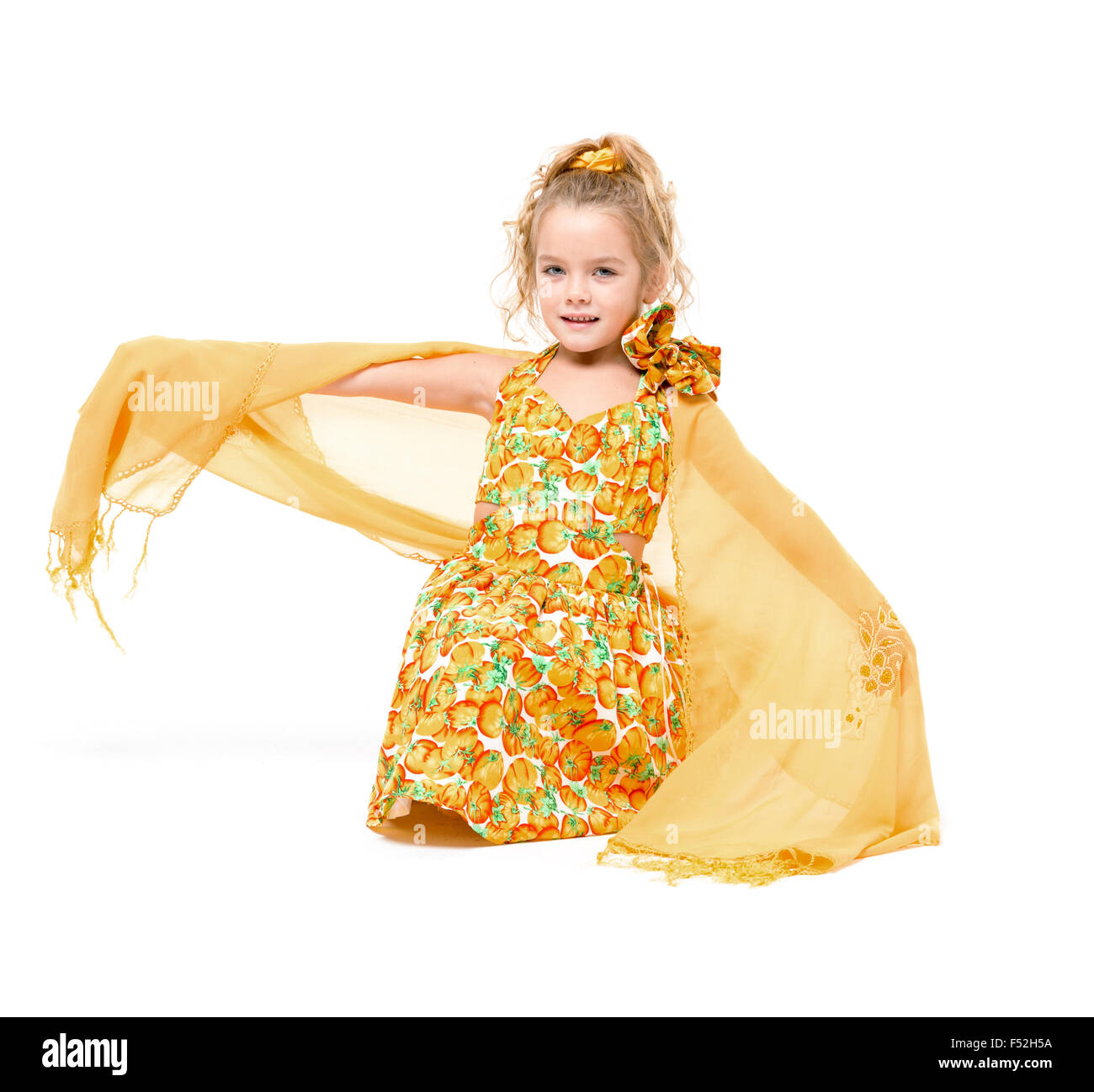 Petite fille dans une robe jaune avec châle posant, sur fond blanc Banque D'Images