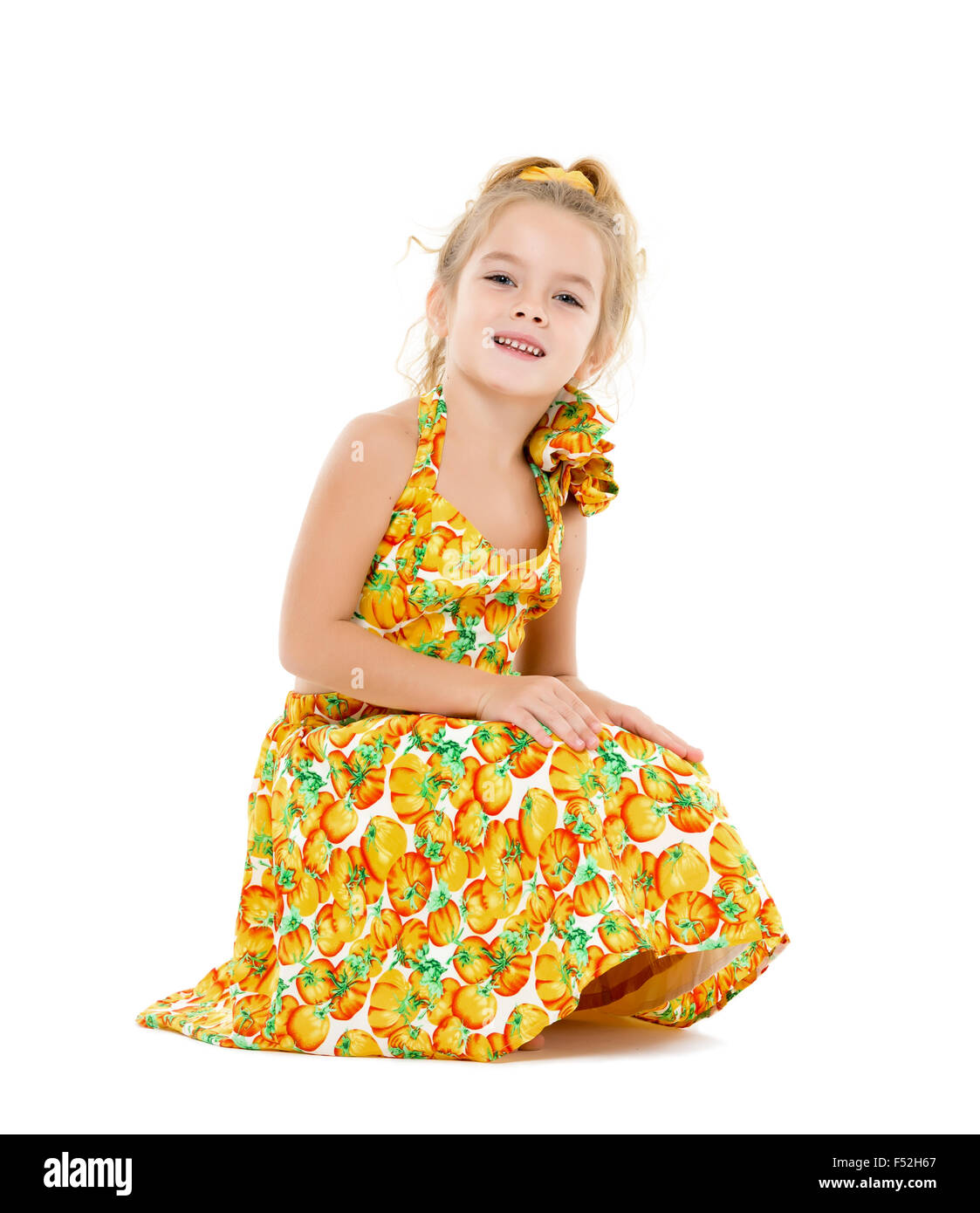 Petite fille dans une robe jaune, posant sur fond blanc Banque D'Images
