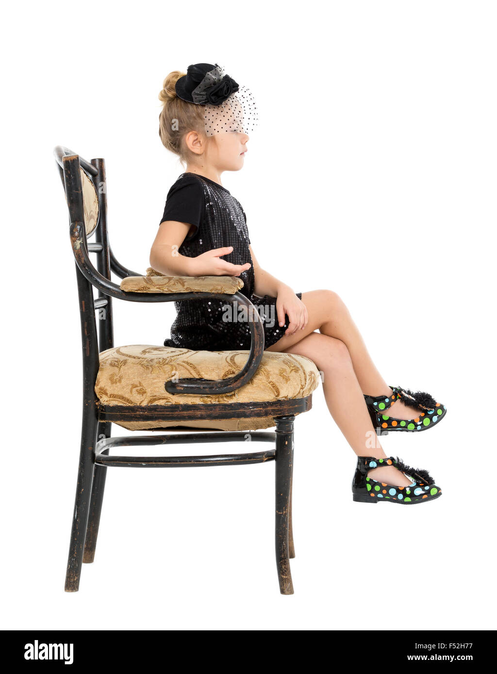 Petite fille assise dans la chaise ancienne, sur fond blanc Banque D'Images