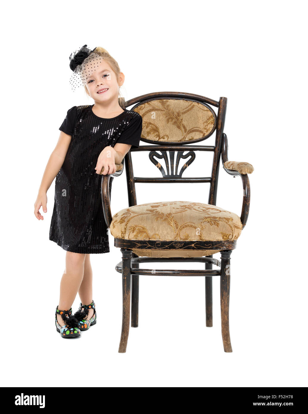 Petite fille debout près de chaise ancienne, sur fond blanc Banque D'Images