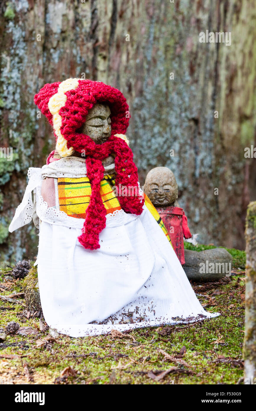 Koyasan, Okunoin cemetery. Les Jizo bosatsu statue bouddhiste avec soumission jaune, rouge et blanc Chapeau tricoté drapé sur carénage, en face de cèdre du tronc. Banque D'Images