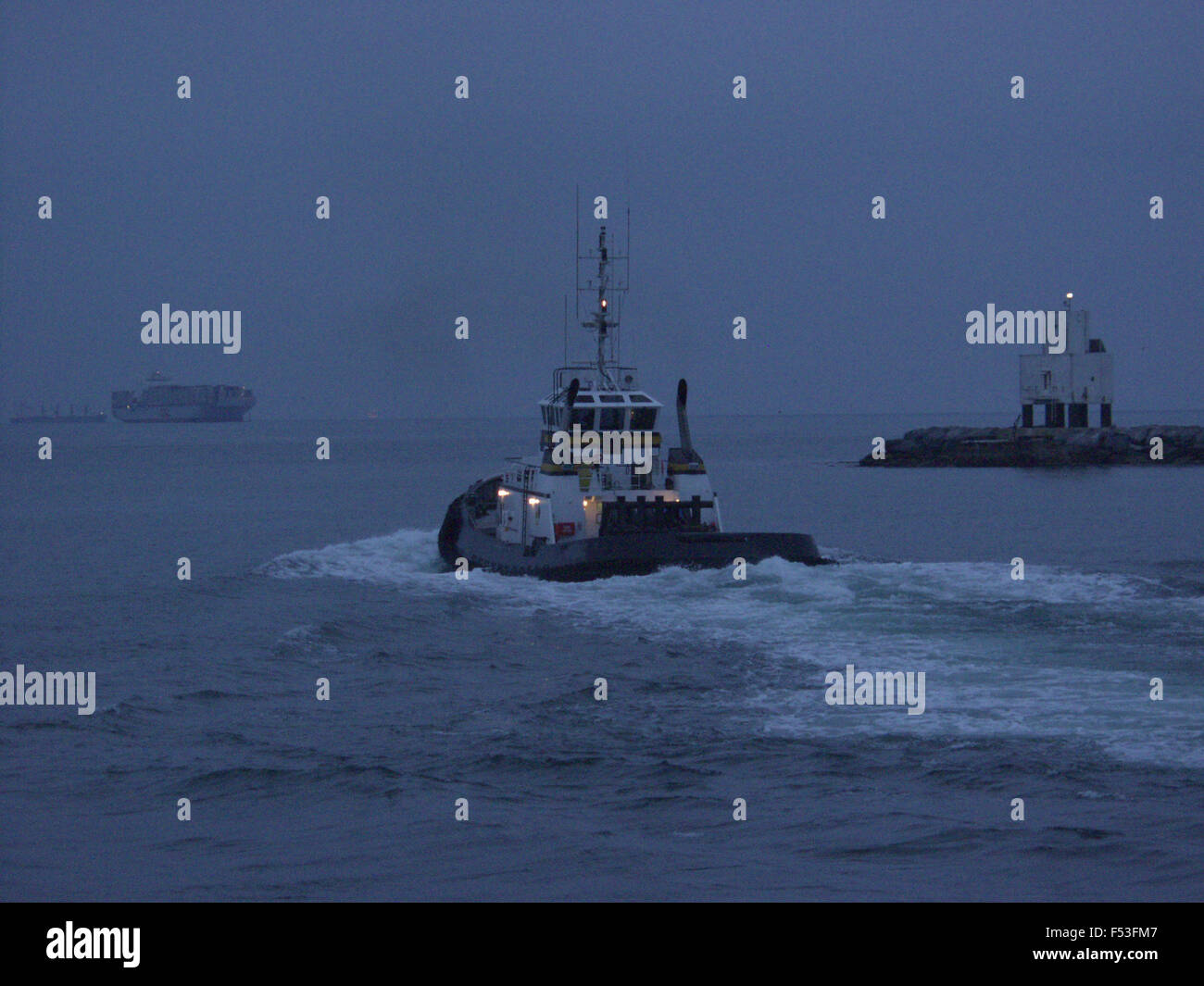 Tug boat sailing out pour aider les porte-conteneurs Banque D'Images