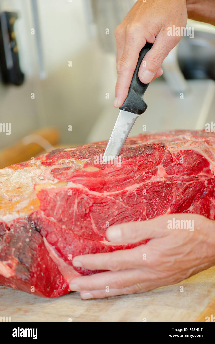 Boucher le port d'un gant pendant que la viande de boeuf coupe Banque D'Images