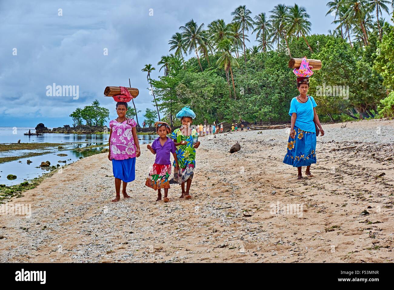 Woman walking along beach boulevard exerçant son fardeau sur leurs têtes Kiriwina. PNG Île Banque D'Images