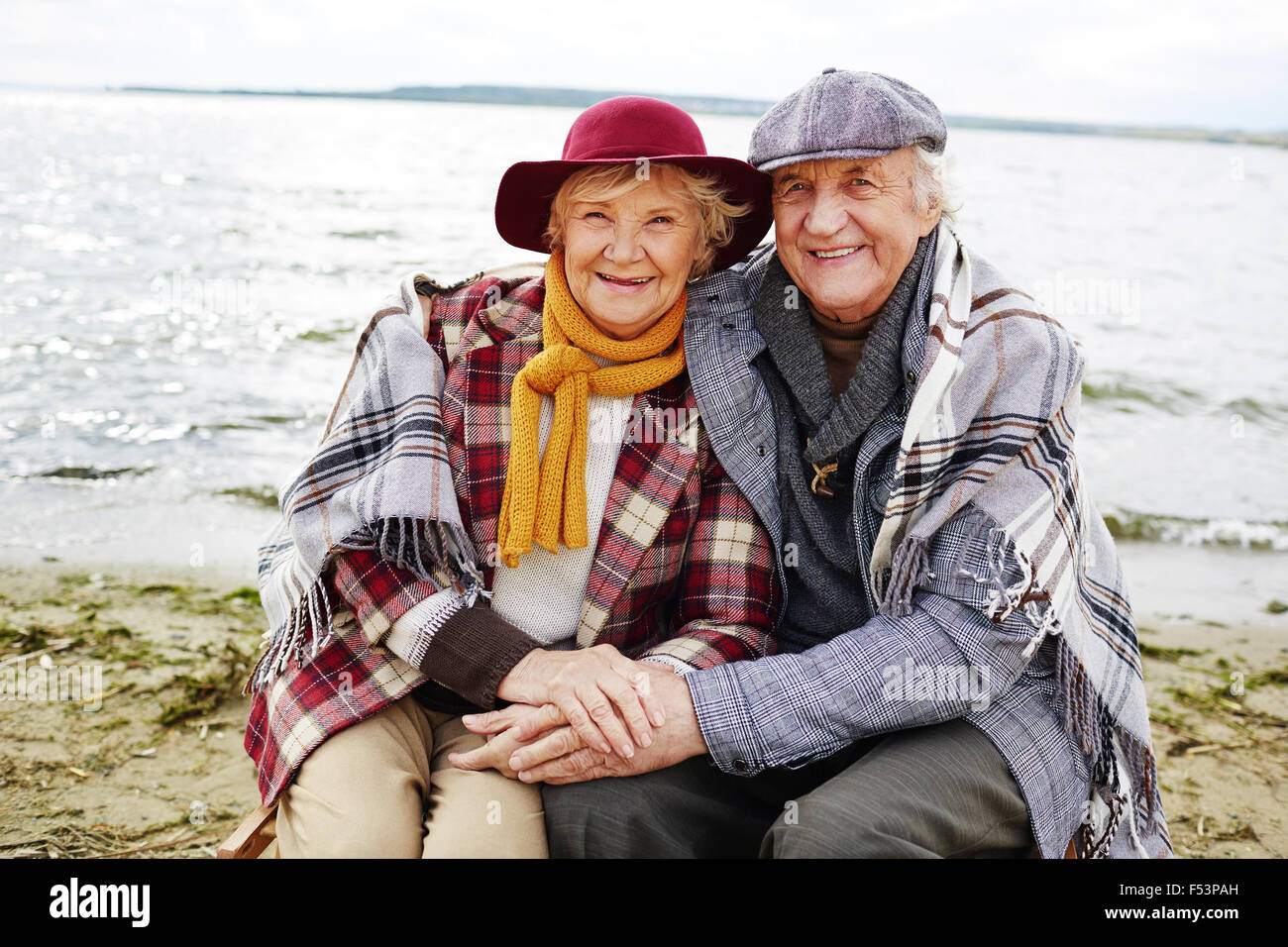 Senior couple embracing and looking at camera près de l'eau Banque D'Images
