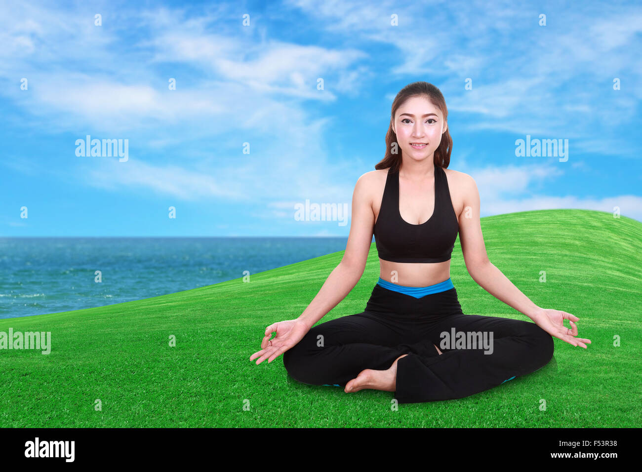 Young woman doing yoga exercice sur l'herbe avec sky Banque D'Images