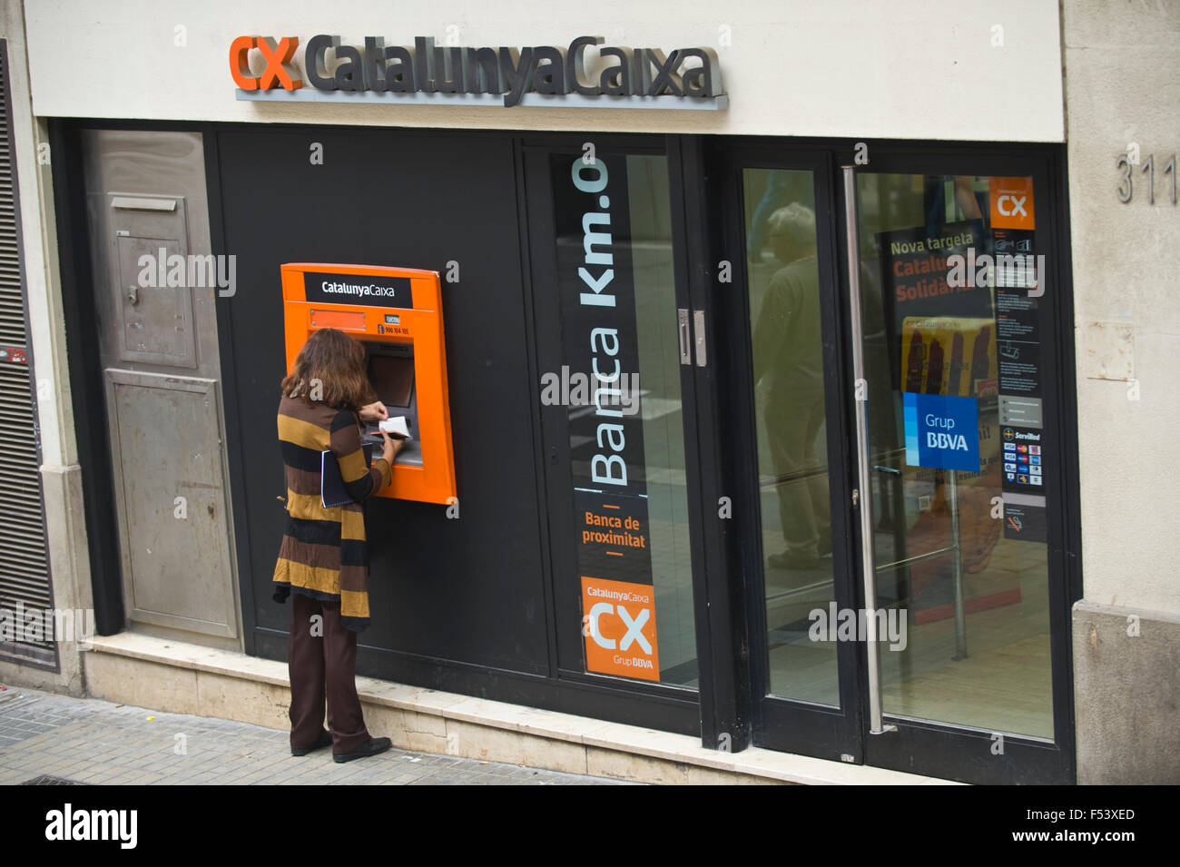 Femme à l'aide d'un distributeur automatique de billets sur rue dans Barcelone Catalogne Espagne ES Banque D'Images