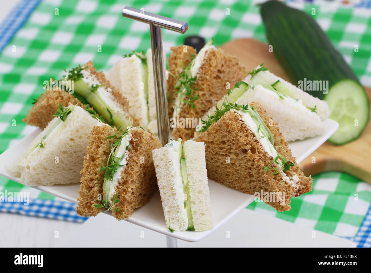 Le blanc et le brun le fromage à la crème et sandwichs au concombre sur le plateau de gâteau Banque D'Images