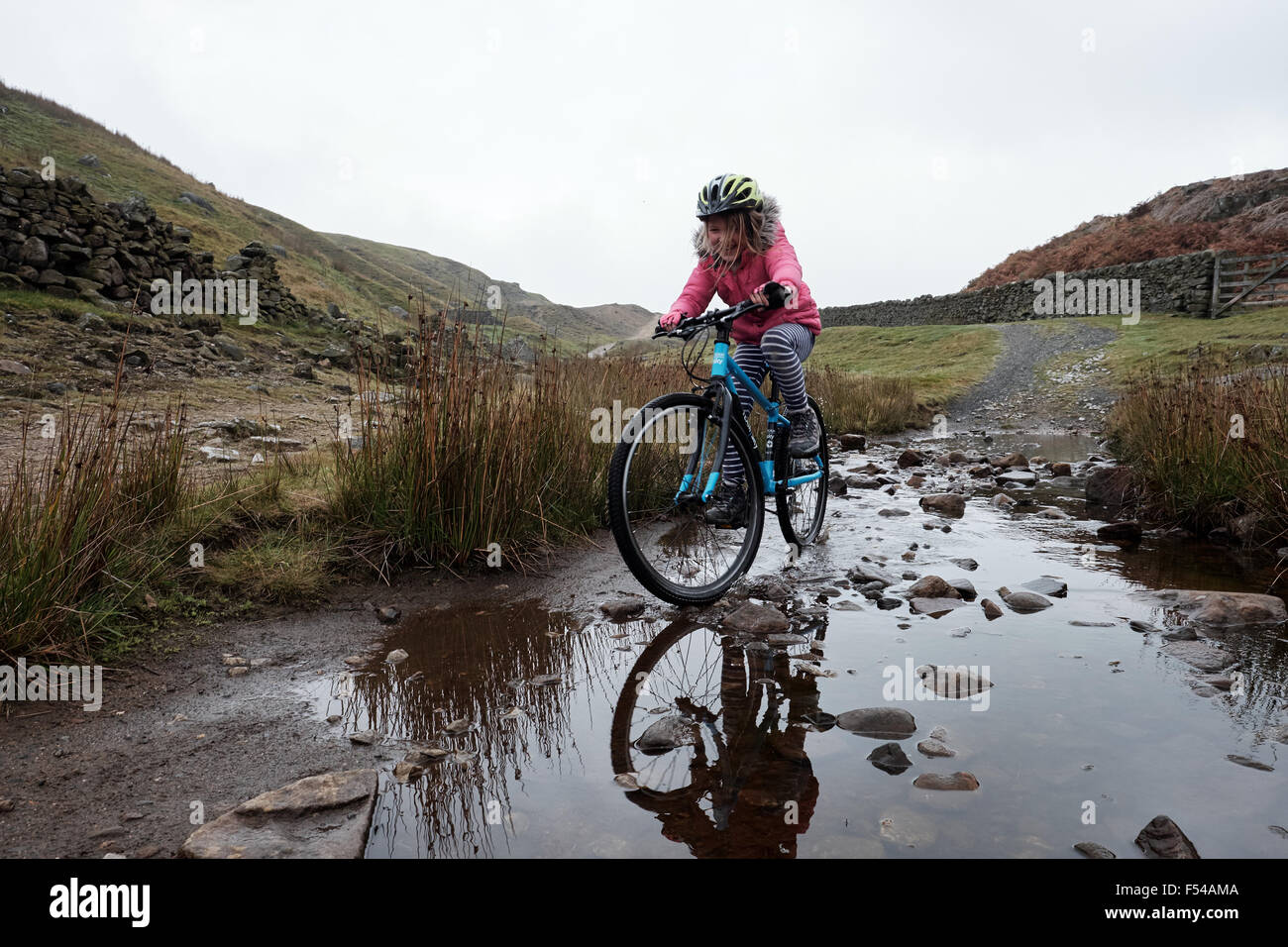 Une fille à cheval son bike off road à travers un ruisseau à plaisir Photo  Stock - Alamy