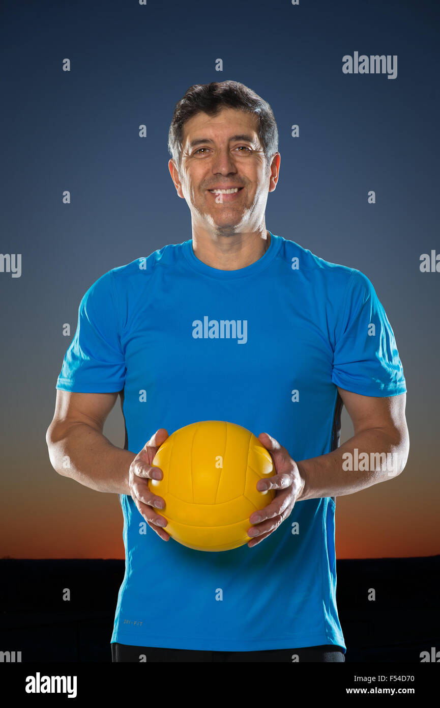 Portrait of mature man holding volley-ball avec coucher du soleil en arrière-plan Banque D'Images