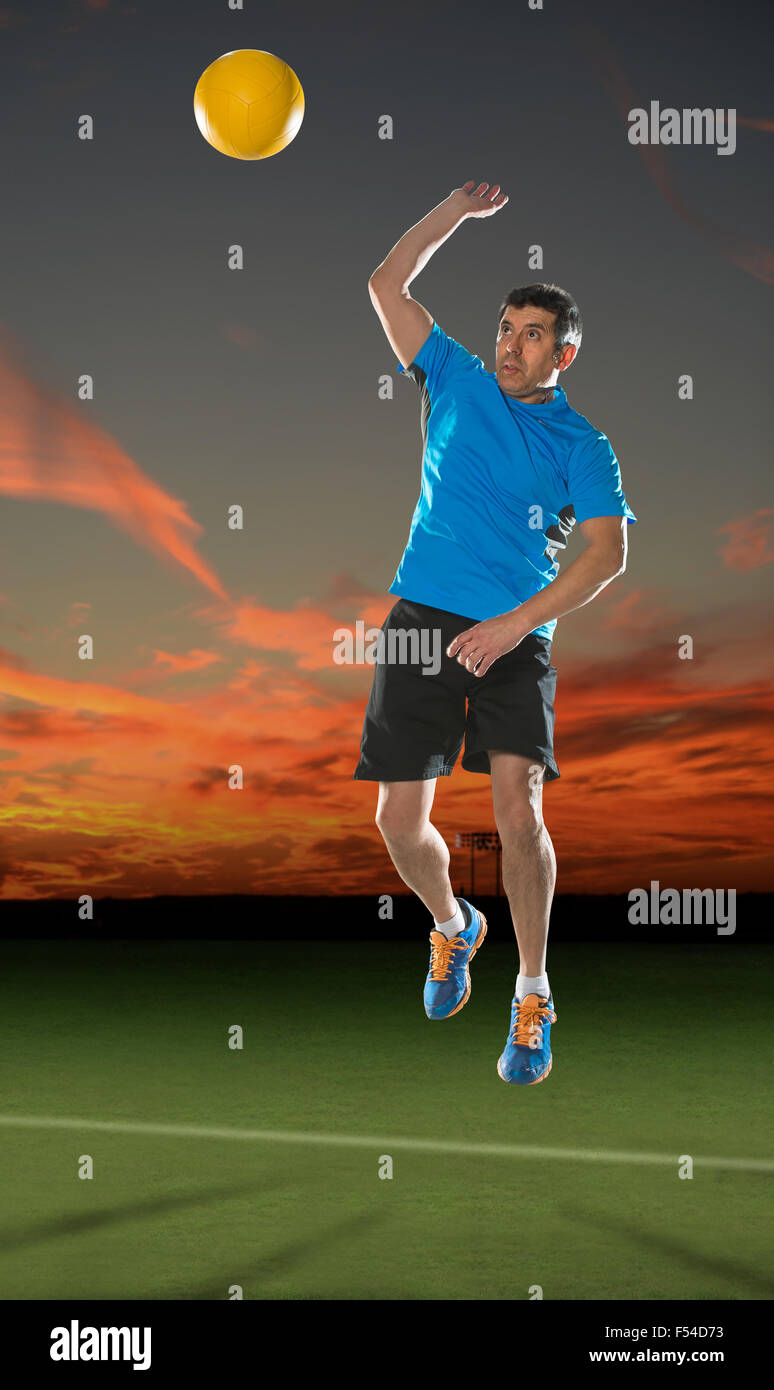 Hot man au service de volley-ball au coucher du soleil Banque D'Images