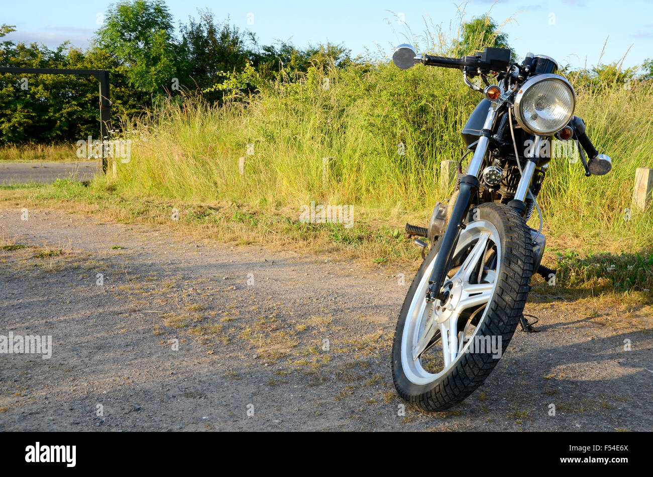 Cafe Racer Honda Moto en noir photographié devant un champ d'herbe Banque D'Images