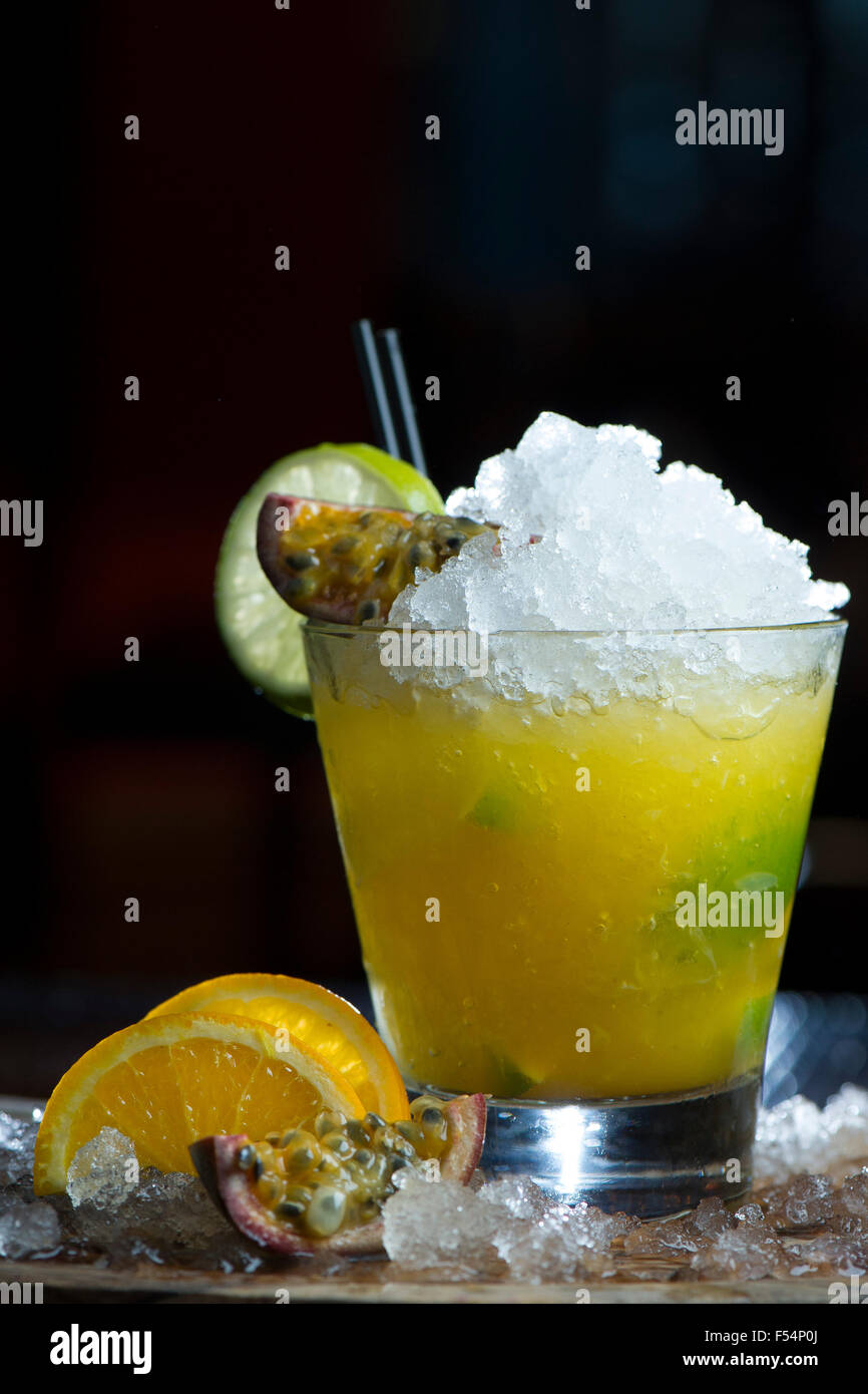 Un cocktail de fruits de la passion jaune rafraîchissant avec de la glace et des tranches d'orange. Banque D'Images