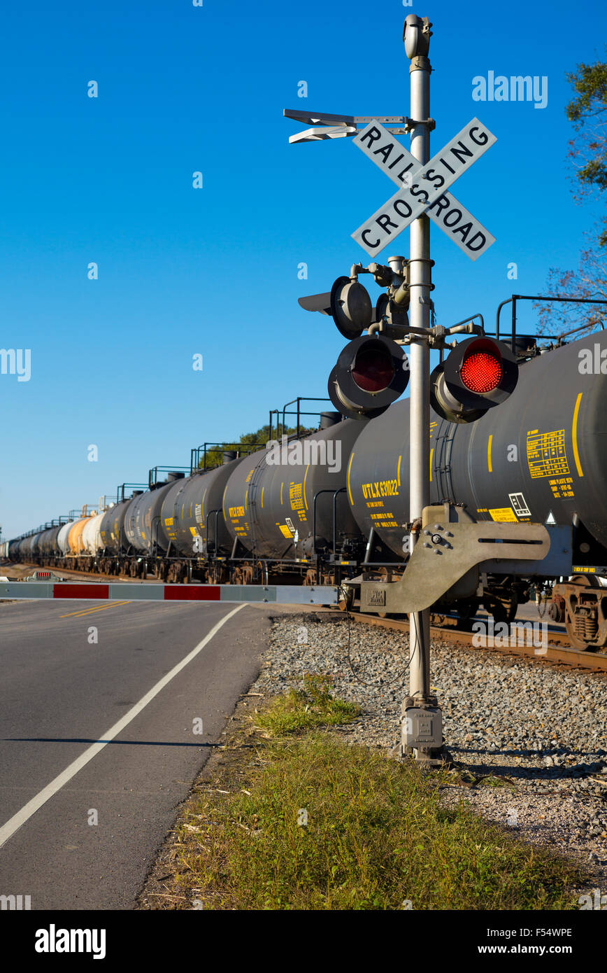 Train de fret des camions-citernes et wagons de chemin de fer au croisement avec les feux rouges en Louisiane, USA Banque D'Images