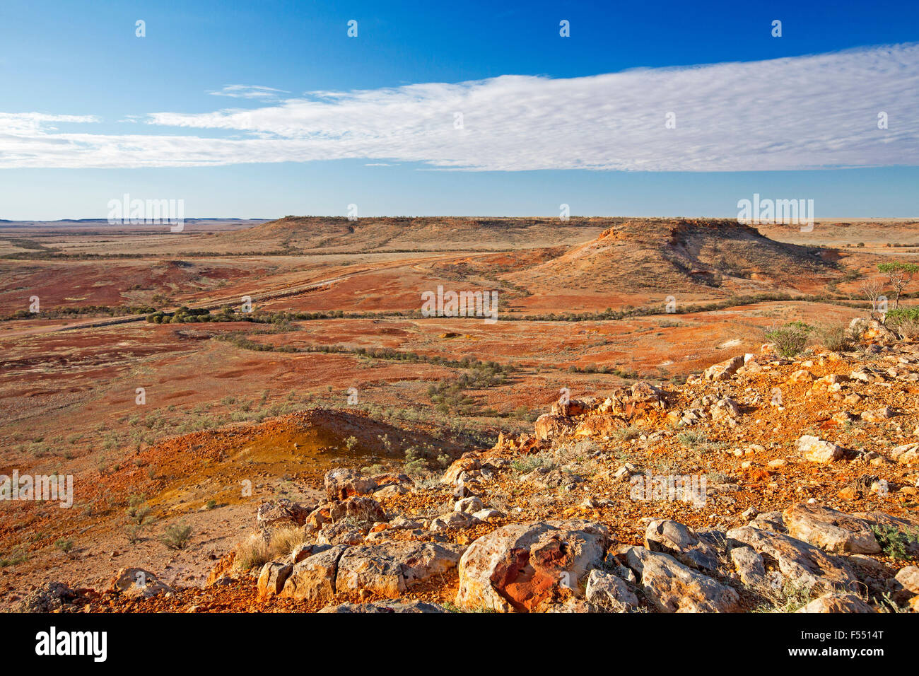 Australian Outback imprenable paysage de colline lookout, mesas rocheuses dénudées sur de vastes plaines sans arbres, s'étendant jusqu'à rouge horizon et ciel bleu Banque D'Images