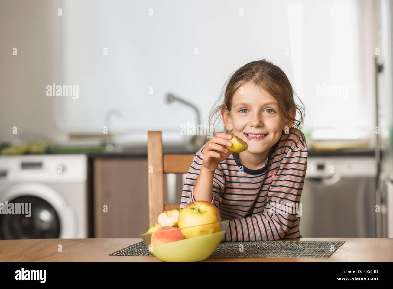 Portrait of happy girl eating apple à la table Banque D'Images