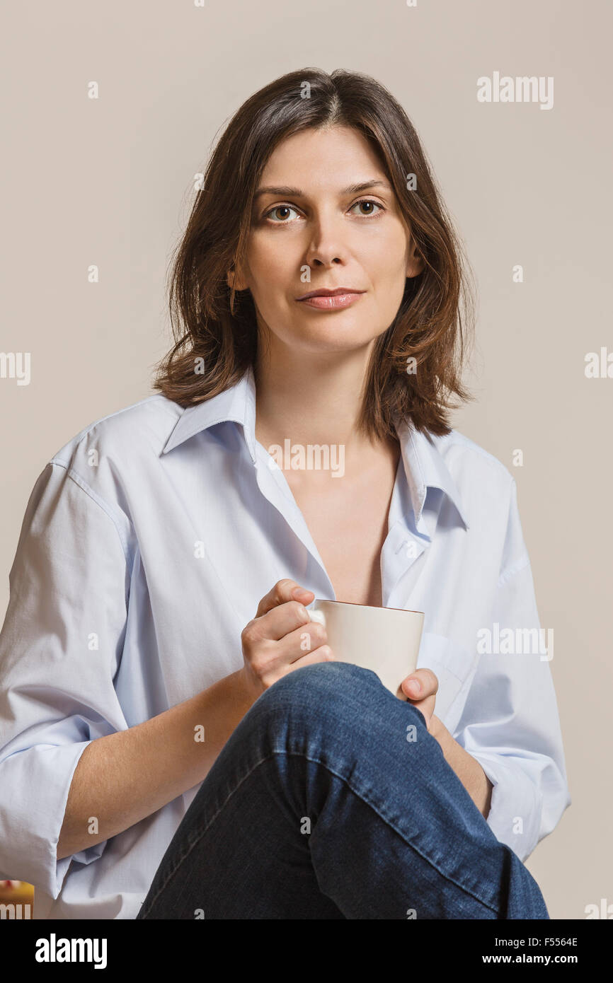 Portrait of woman holding coffee mug against white background Banque D'Images