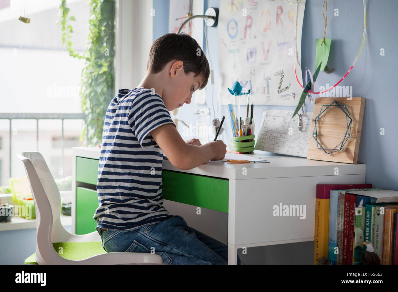 Vue latérale du boy doing homework at table in house Banque D'Images