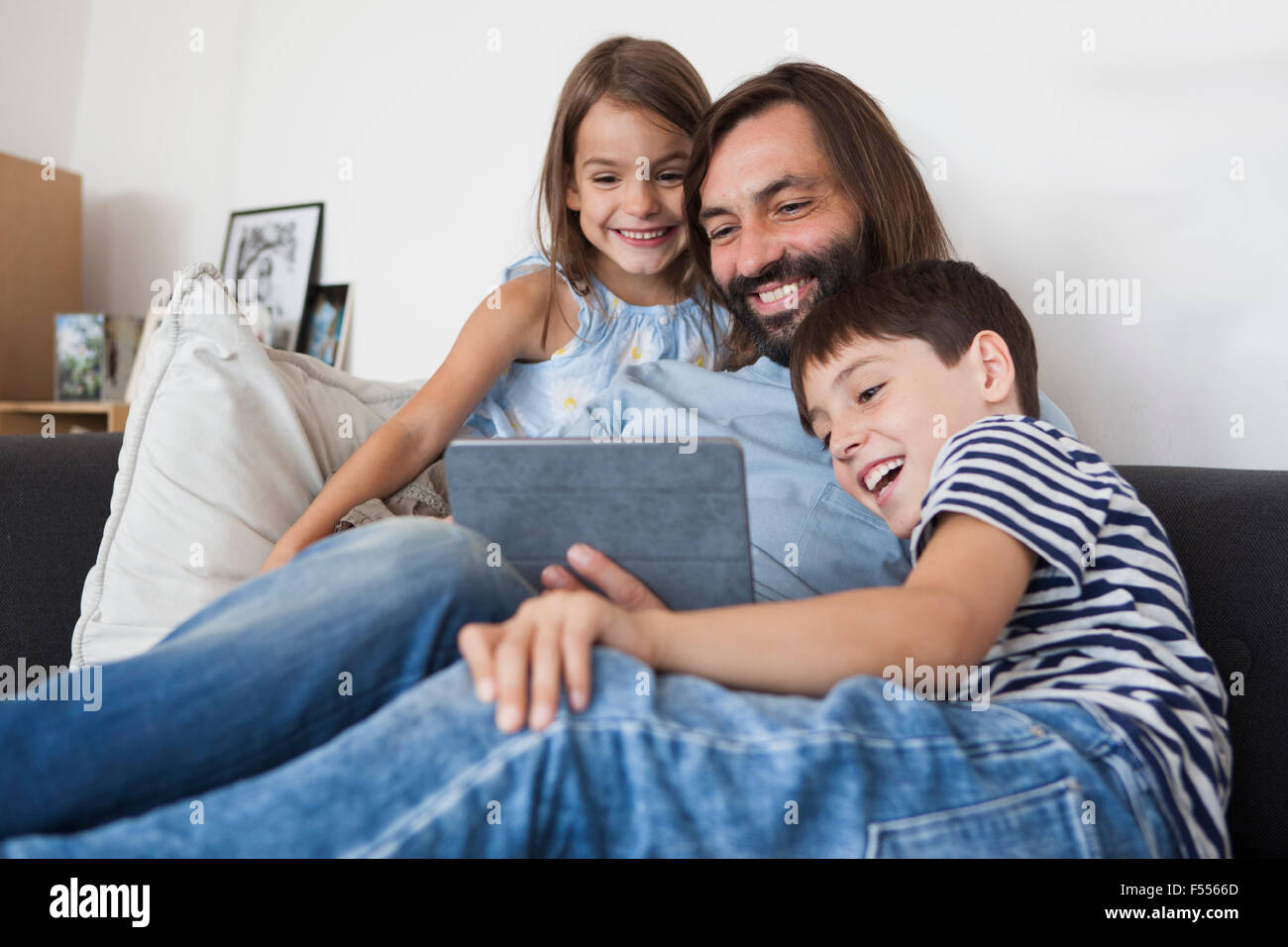 Heureux père avec enfants sitting on sofa at home Banque D'Images