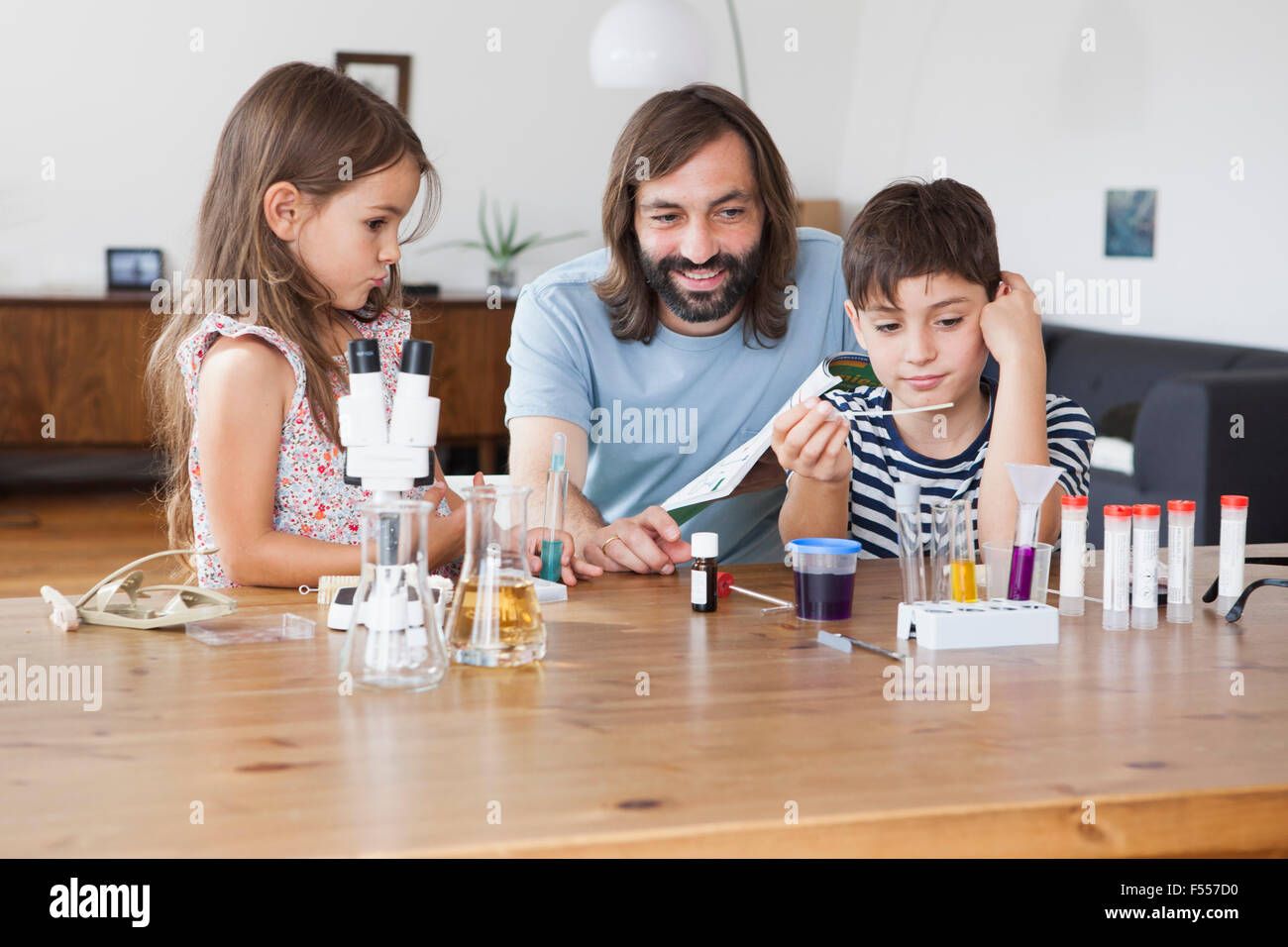 Heureux père et enfants faisant l'école à la maison de projet scientifique Banque D'Images