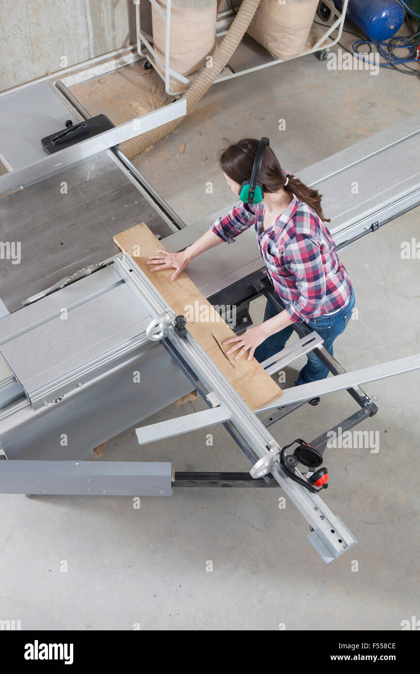 Une femme à l'aide d'un menuisier Scie sur table coulissante dans un atelier Banque D'Images