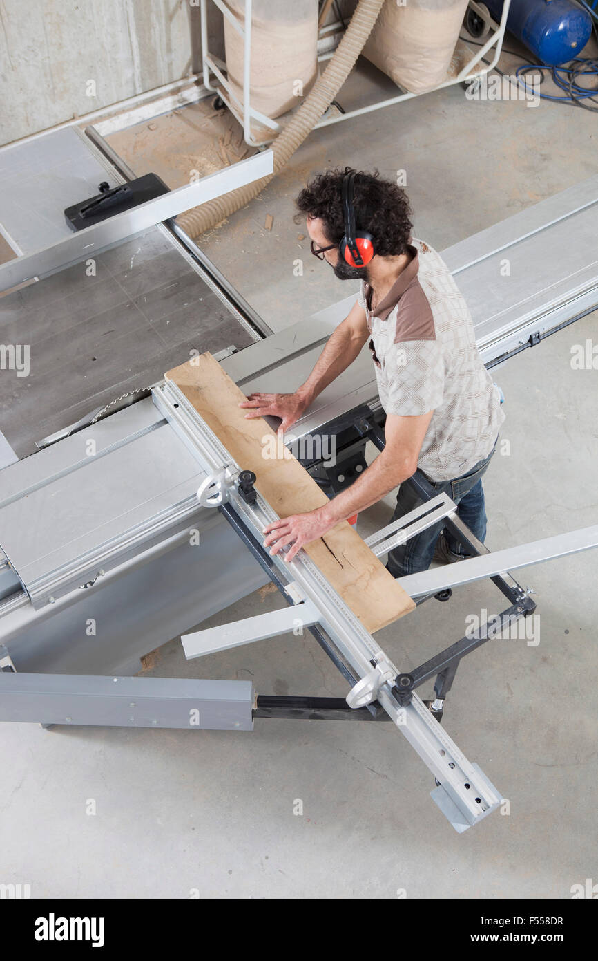 High angle view of Carpenter à l'aide d'une scie sur table coulissante en atelier Banque D'Images