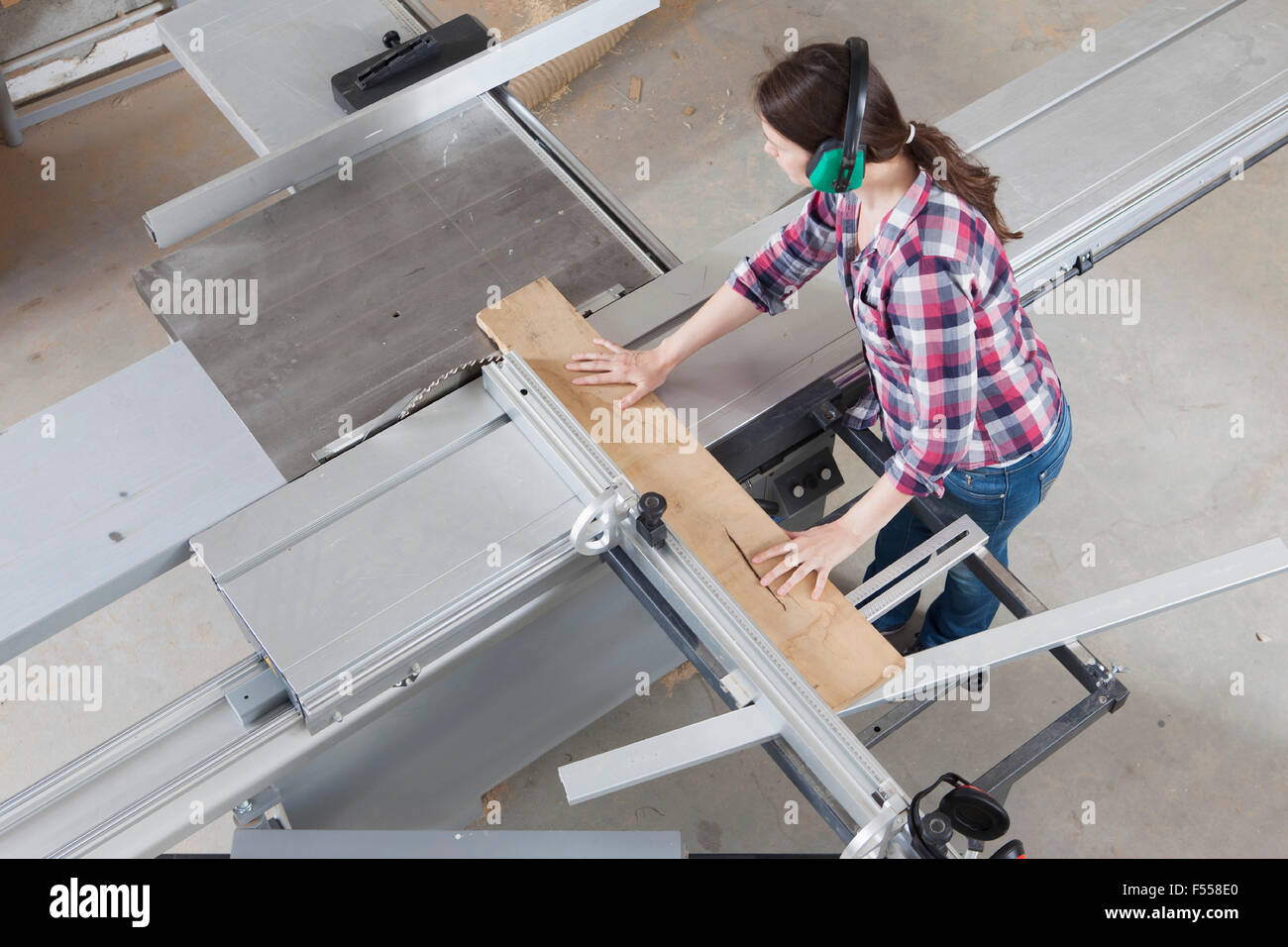 High angle view of female Carpenter à l'aide d'une scie sur table coulissante en atelier Banque D'Images