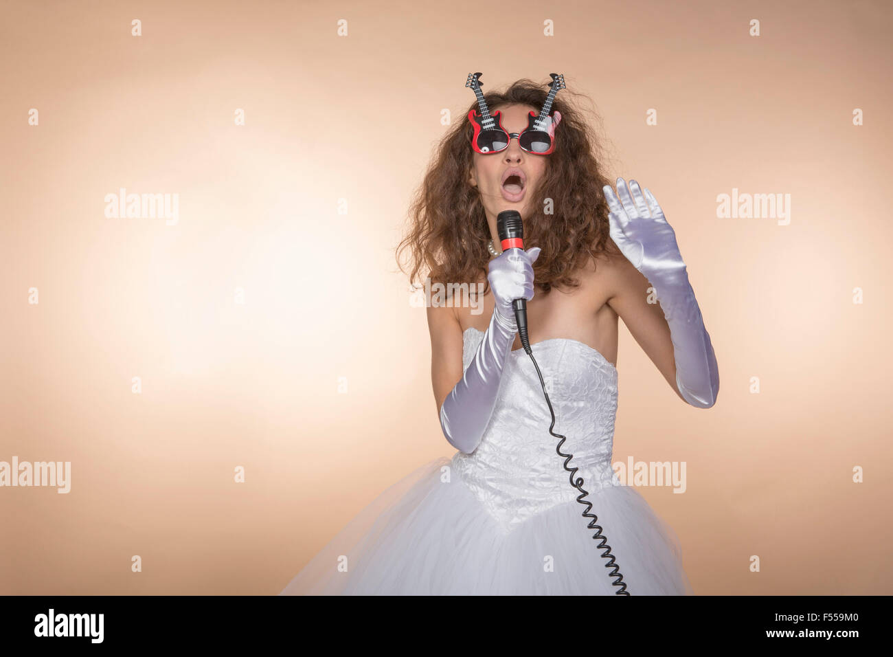En forme de guitare en mariée excités chant lunettes contre l'arrière-plan de couleur Banque D'Images