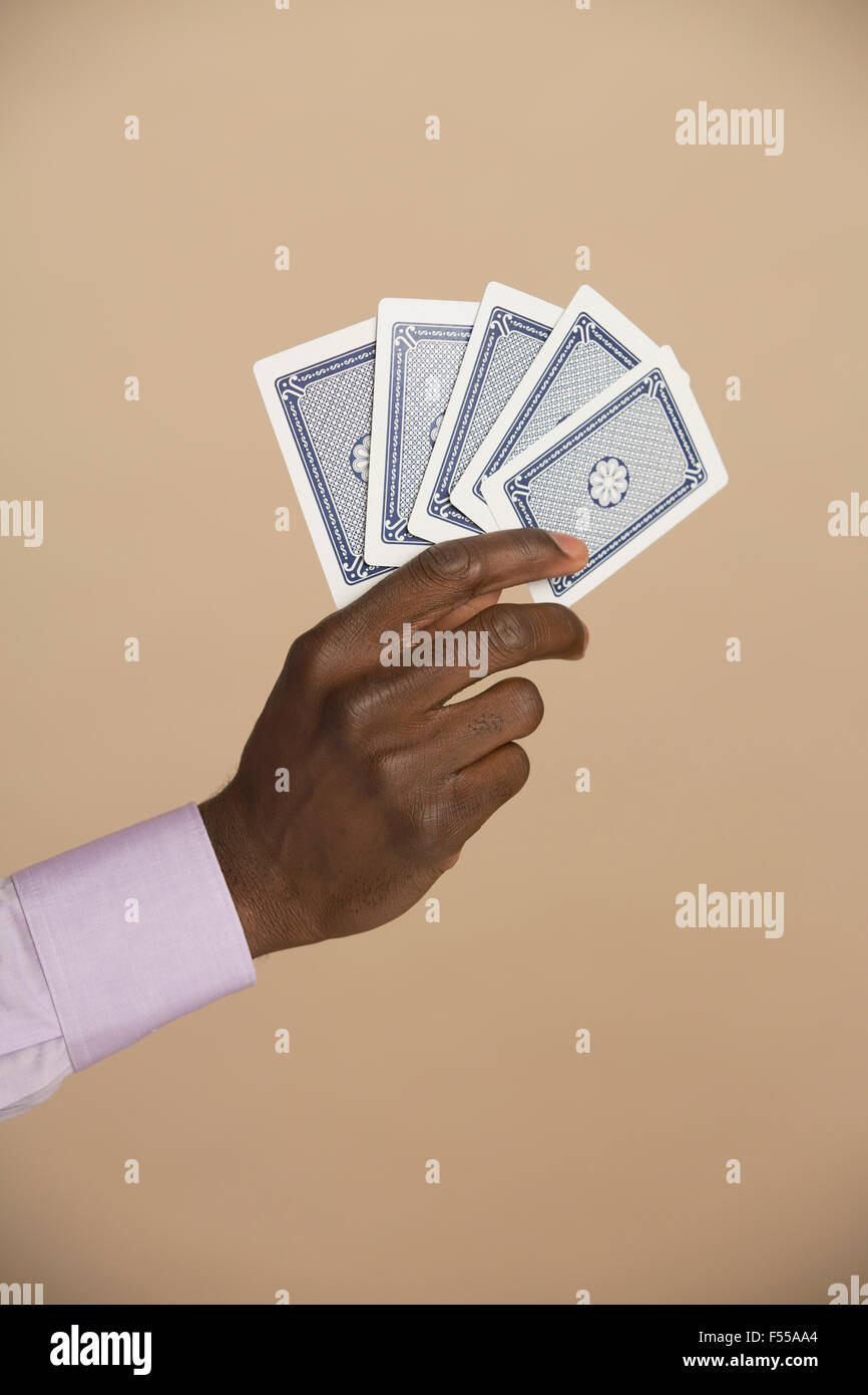 Cropped hand holding cartes à jouer contre l'arrière-plan de couleur Banque D'Images