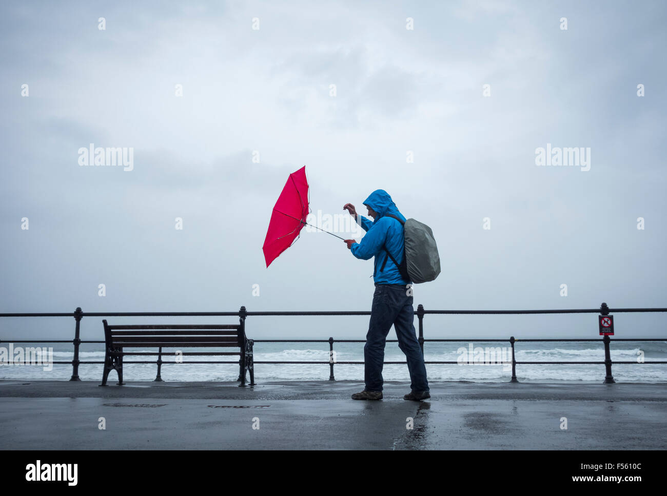 Homme avec un parapluie rouge le jour du vent/de l'orage. ROYAUME-UNI Banque D'Images