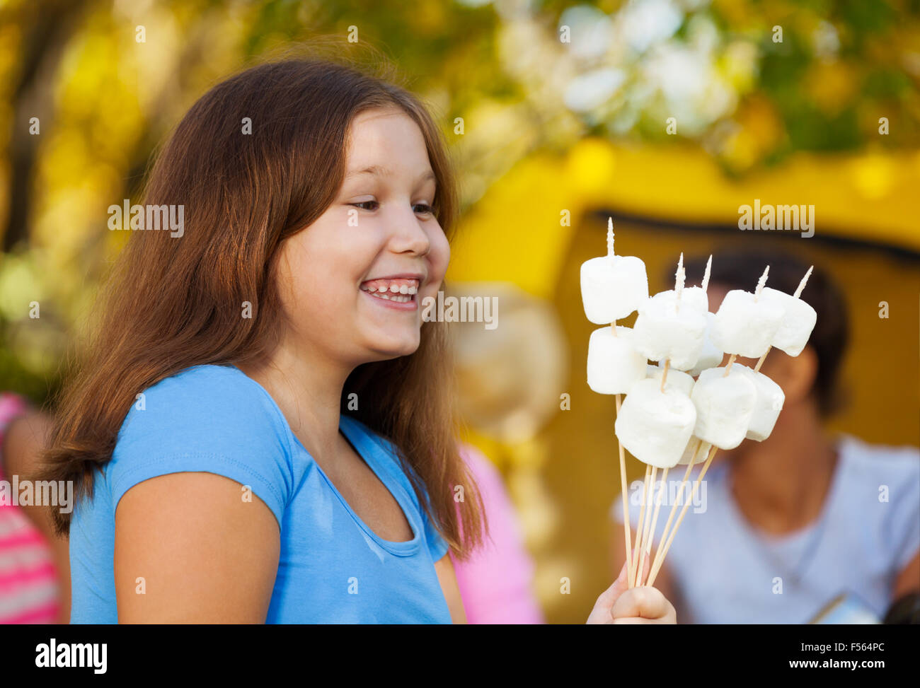 Cute girl positive est titulaire d'bâtons avec de la guimauve Banque D'Images