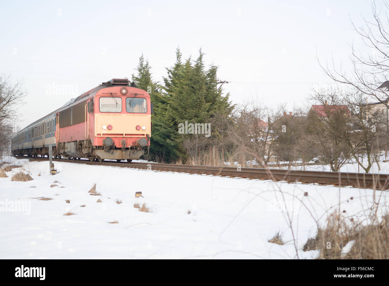 La locomotive rouge et jaune avec des trains de voyageurs Wagons bleu en hiver à une journée Village couvert de neige Banque D'Images
