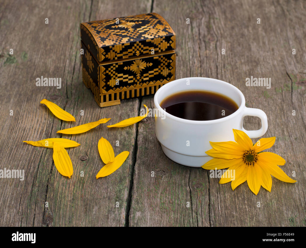 Tasse de café, des pétales, et fleur jaune, still life, sur une table en bois Banque D'Images