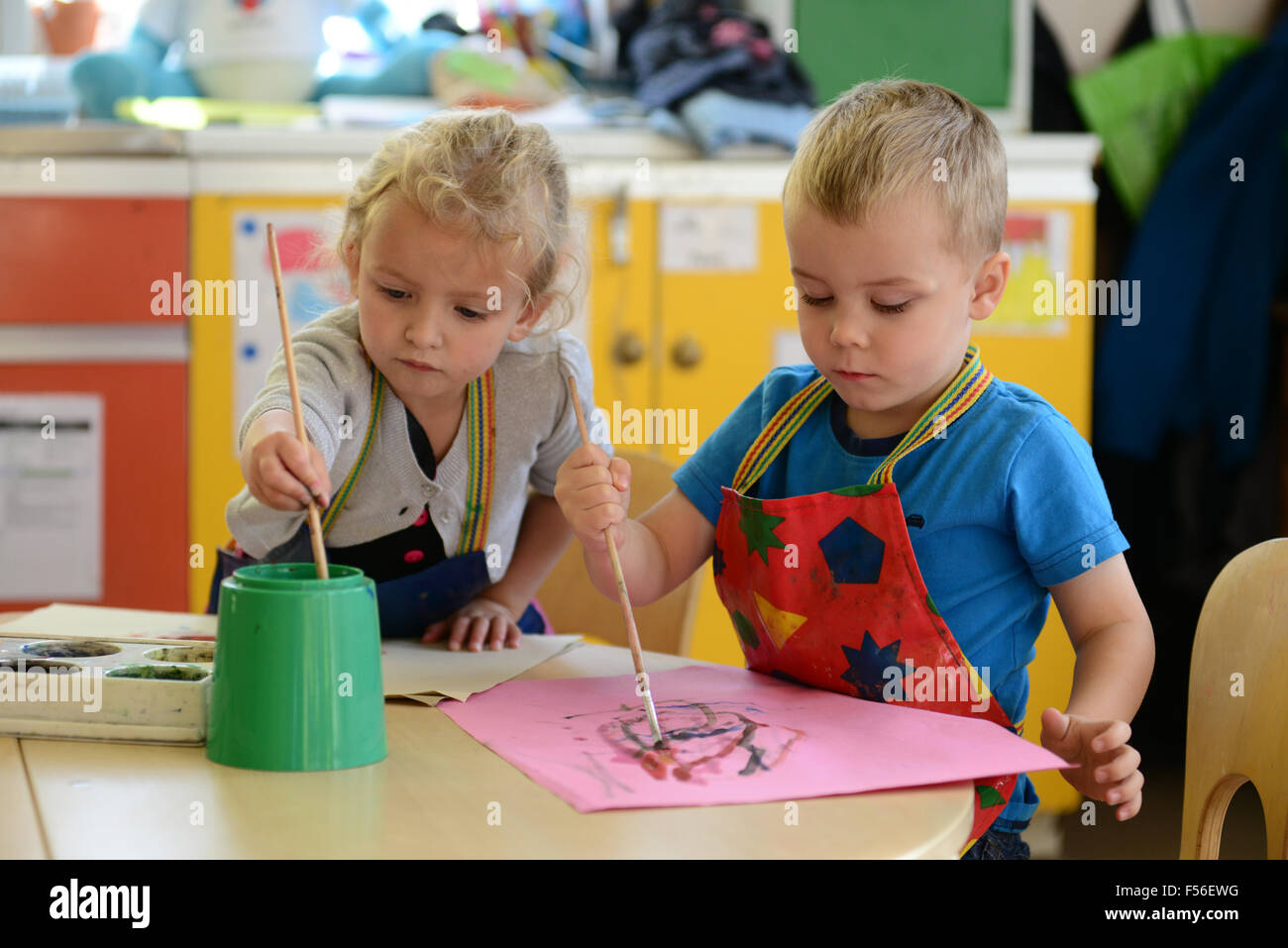 Une petite fille et garçon en peinture à l'école maternelle. Banque D'Images